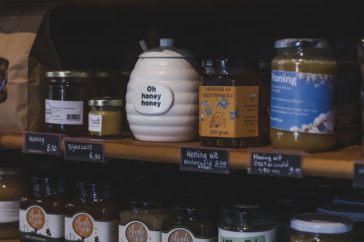Explore artisanal honey jars and local products neatly displayed on wooden shelves in a charming Dutch shop.